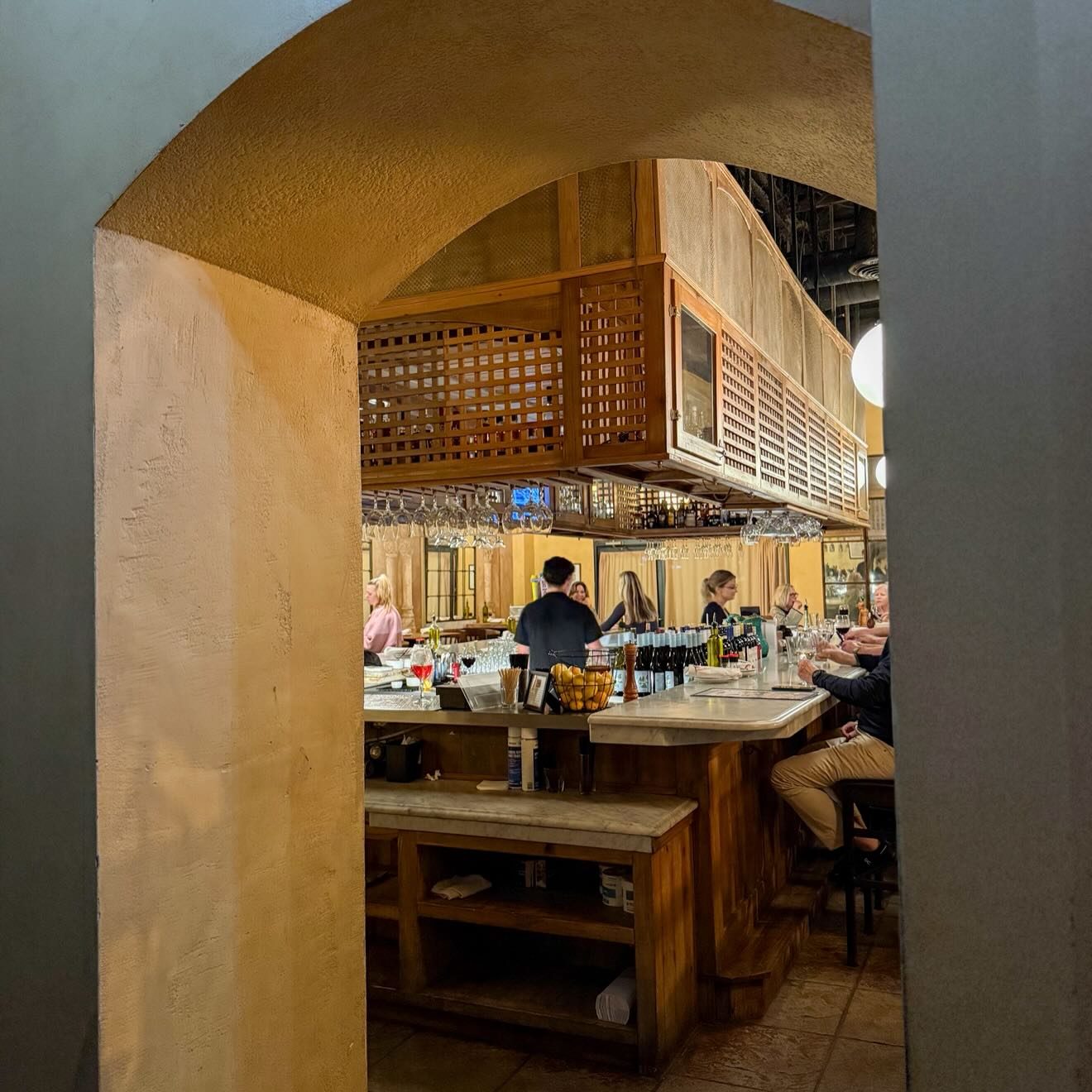 The bar at Osteria Cicchetti seen through a plaster archway