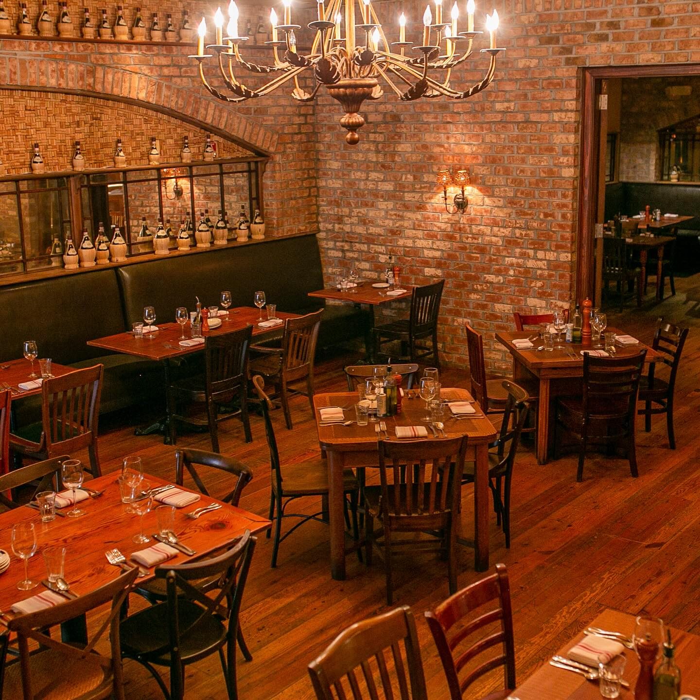 The brick dining room at Osteria Cicchetti with its chandelier, set for dinner